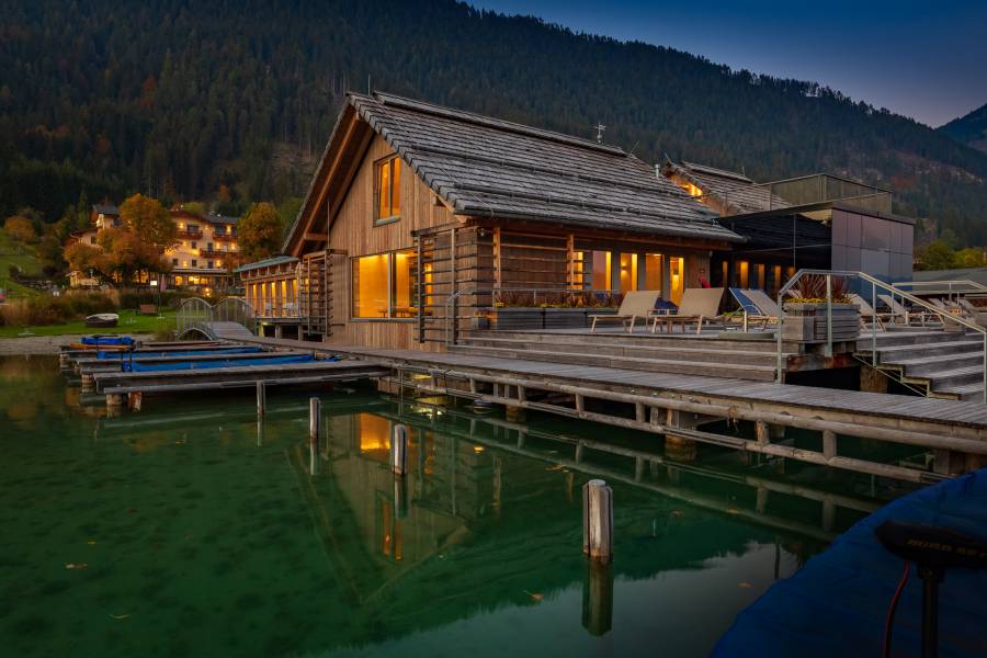 External view of the illuminated lake-spa in the evening  Strandhotel am Weissensee